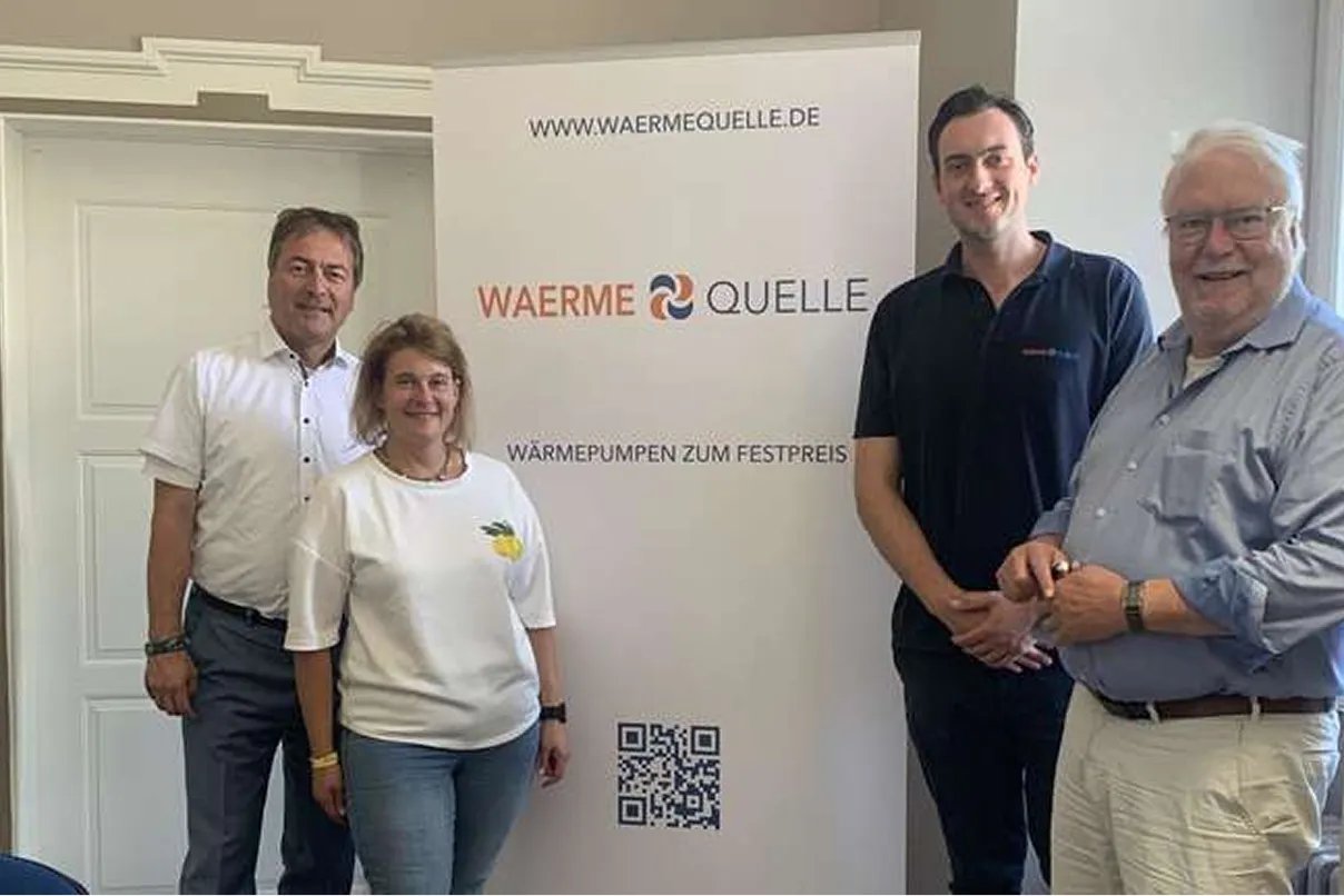 Youri Kissner, Geschäftsführer der Waermequelle GmbH, mit drei weiteren Personen vor einem Waermequelle Rollup Plakat.
