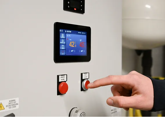 Nahaufnahme des Bedienpanels einer Waermequelle Wärmepumpe mit Touchscreen, auf den mit einem Finger gezeigt wird.