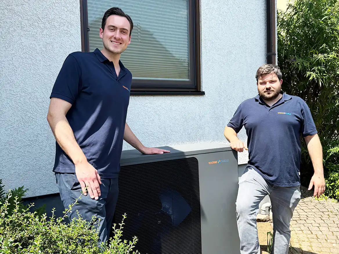 Die Geschäftsführer der Waermequelle GmbH, Youri Kissner und Felix Cvecko, neben einer Wärmepumpe stehend.