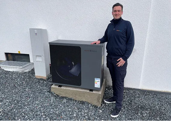 Geschäftsführer der Waermequelle GmbH, Youri Kissner, neben einer Wärmepumpe vor einem Haus stehend.