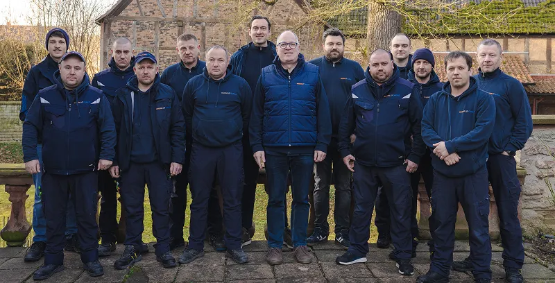 Das Team von Waermequelle: Viele Menschen in dunkelblauer Arbeitskleidung nebeneinander.