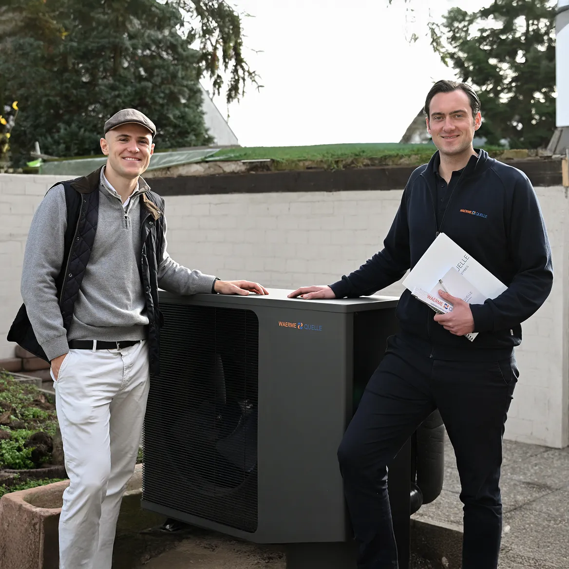 Youri Kissner, Geschäftsführer der Waermequelle GmbH, mit einem Kunden vor einer Wärmepumpe stehend.