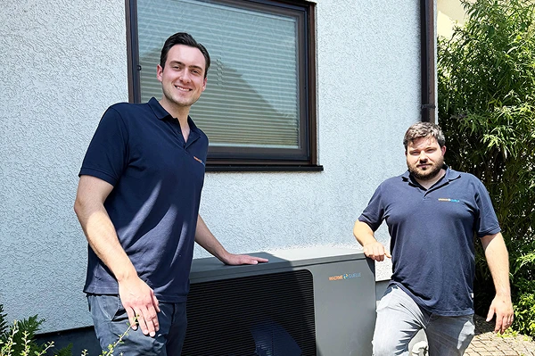 Die Geschäftsführer der Waermequelle GmbH, Youri Kissner und Felix Cvecko, neben einer Wärmepumpe stehend.