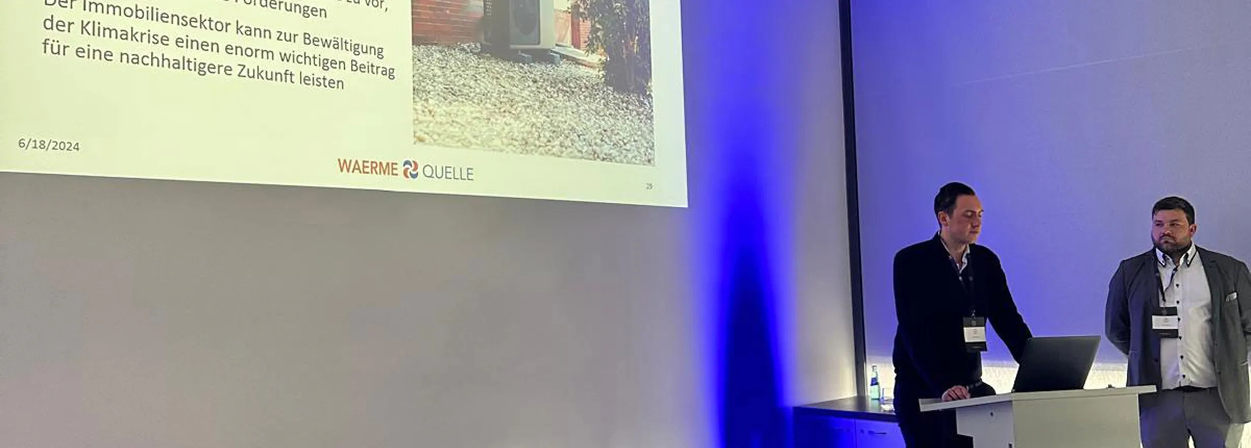 Youri Kissner und Felix Cvecko, Geschäftsführer der Waermequelle GmbH, an einem Redepult vor einer PowerPoint-Präsentation.