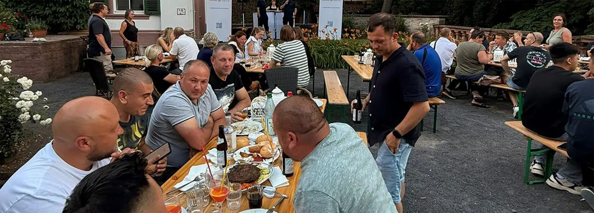 Das Waermequelle Team auf mehreren Bierbänken und mit Essen auf dem Tisch im Freien sitzend.