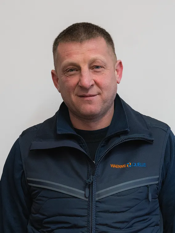 Porträt eines Mitarbeiters der Waermequelle GmbH mit dunkelblauer Jacke mit Waermequelle Logo.