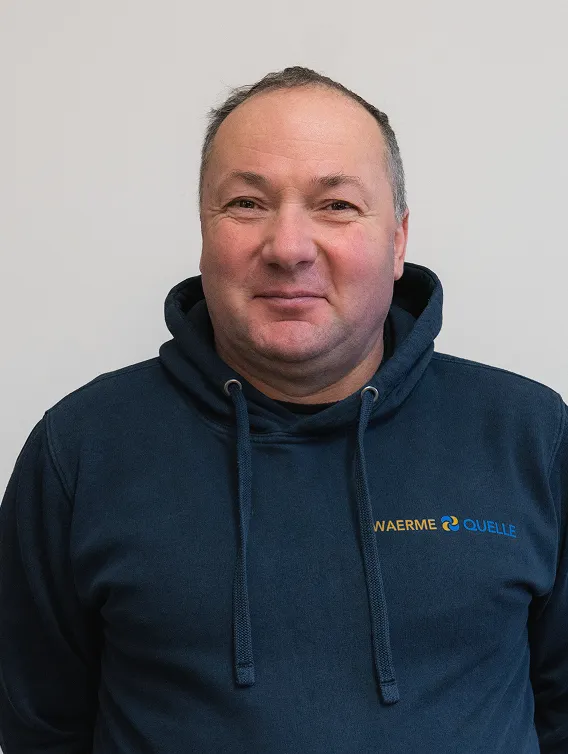 Porträt eines Mitarbeiters der Waermequelle GmbH mit dunkelblauer Jacke mit Waermequelle Logo.