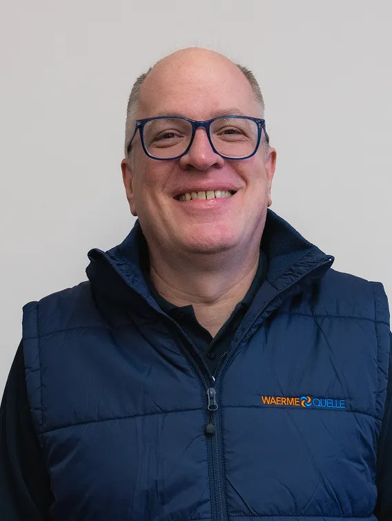 Porträt eines Mitarbeiters der Waermequelle GmbH mit dunkelblauer Jacke mit Waermequelle Logo.
