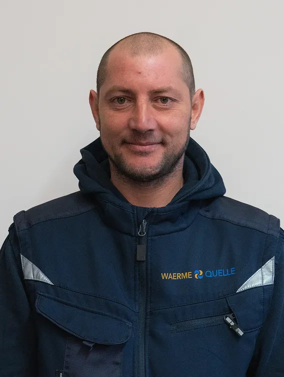 Porträt eines Mitarbeiters der Waermequelle GmbH mit dunkelblauer Jacke mit Waermequelle Logo.