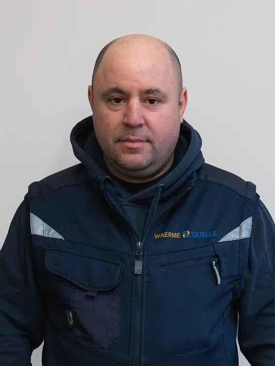 Porträt eines Mitarbeiters der Waermequelle GmbH mit dunkelblauer Jacke mit Waermequelle Logo.